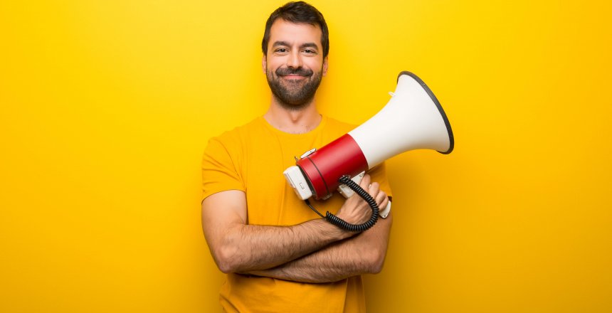 Man on isolated vibrant yellow color holding a megaphone